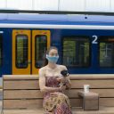 Vrouw draagt een mondkapje op het perron in Amsterdam, foto: ANP