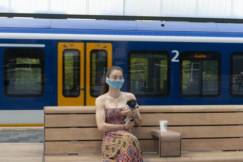 Vrouw draagt een mondkapje op het perron in Amsterdam, foto: ANP