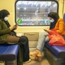 Twee jonge moslima's zitten in de trein op hun telefoon te kijken
