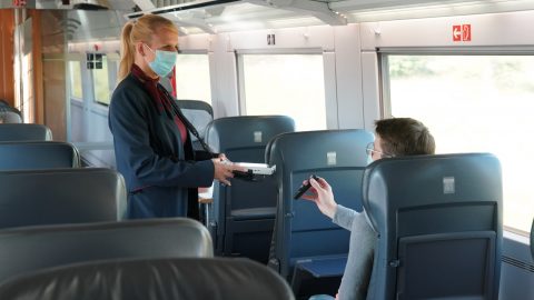 Conducteur met mondkapje controleert reiziger ICE trein